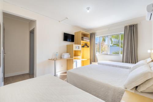 a hotel room with two beds and a window at Hotel Rosenbrock in Balneário Camboriú
