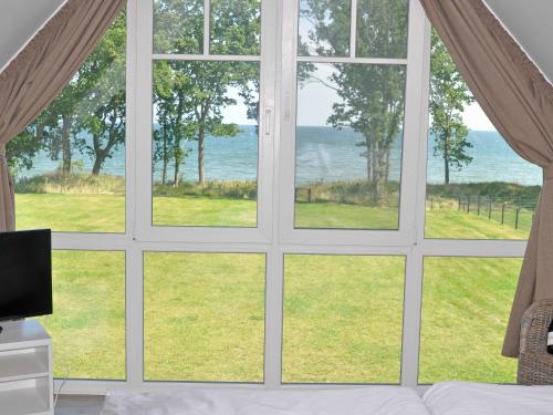 a room with a window looking out at the ocean at Reethus am Strand - Haushälfte 1 mit Kamin, Sauna in Lobbe