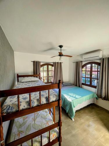 a bedroom with two bunk beds and two windows at Casarão entre Cabo Frio e Búzios Piscina Privativa Ar condicionado, Sinuca, Totó, Churrasqueira 4 quartos Wi-Fi 500mb in Cabo Frio