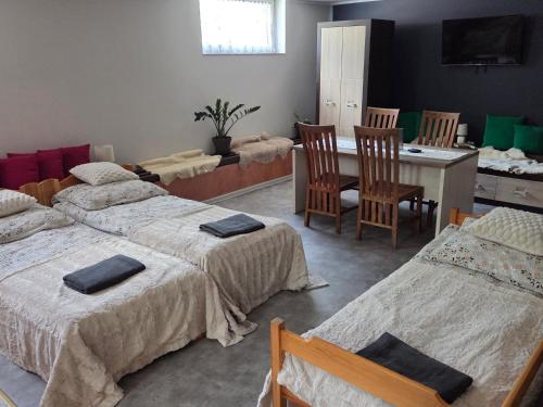 a room with three beds and a table and chairs at BECEJŁY de LUX in Becejły