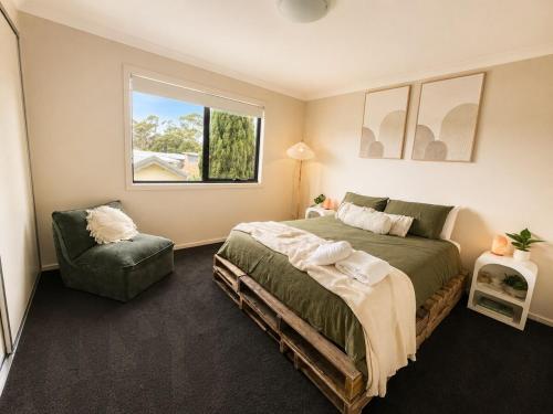 a bedroom with a bed and a chair and a window at The Cozy Corner Retreat in Port Sorell
