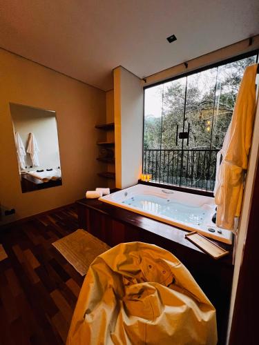 a room with a large window with a hot tub at Shoresh Araucária in Campos do Jordão
