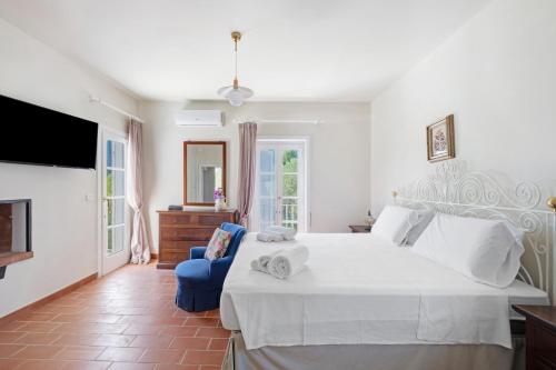 a bedroom with a large white bed and a blue chair at Villa La Cucchiara in Santa Caterina di Nardò