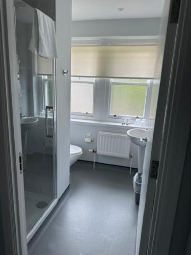 a bathroom with a shower and a toilet and a sink at Hinsley Hall in Leeds