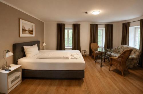 a bedroom with a bed and a table and a chair at Hotel Restaurant El Greco bei der Taffingsmühle in Saarlouis