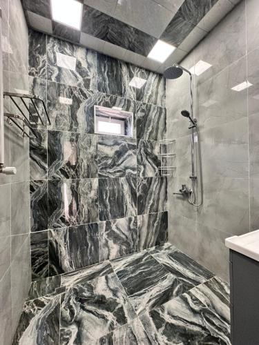 a bathroom with a shower with marble tiles at Peaceful Garden Villa in Gabala