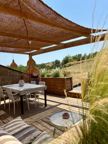 a patio with a table and chairs under a pergola at La Chambrote - Maison, spa privatif & clim in Brive-la-Gaillarde