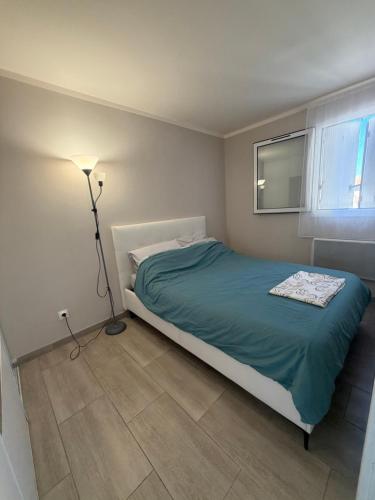 a bedroom with a bed with a lamp and a window at Le venizio Sète in Sète