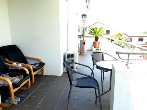 a patio with chairs and a table on a balcony at Lush & Co Auckland Bed & Breakfast in Auckland