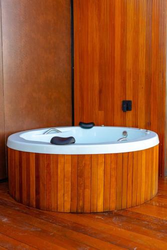 a bath tub in a room with a wooden wall at Refúgio Tapera Bungalows & Wellness in Venda Nova do Imigrante