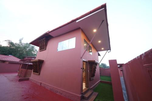 a pink house with a window and a fence at Saj Earth Resort , Cochin Airport in Nedumbassery