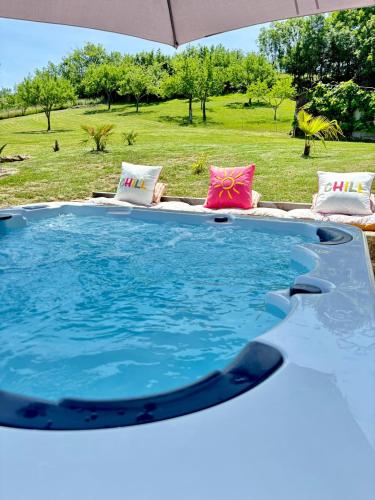 a swimming pool with an umbrella and some chairs at La Chambrote - Maison, spa privatif & clim in Brive-la-Gaillarde