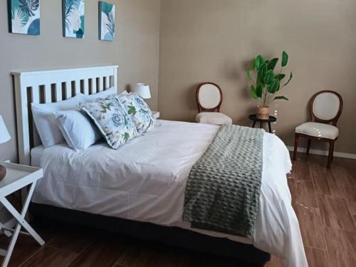 a bedroom with a white bed and two chairs at Cape Karoo Lodge in Riversdale