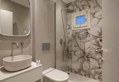 a bathroom with a sink and a toilet and a mirror at AMARÉ suites in Nikiti