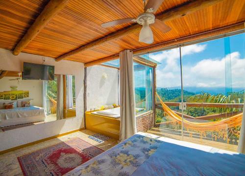 a bedroom with a bed and a large window at Sítio Emanoel Bangalôs in Domingos Martins
