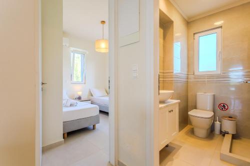a bathroom with a toilet and a sink and a bed at Resitour - Aphrodite Beachfront in Pírgos Psilonérou
