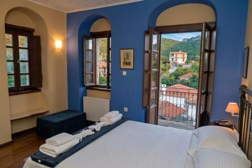 a blue bedroom with a bed and a large window at Archontiko Leontari in Leondari