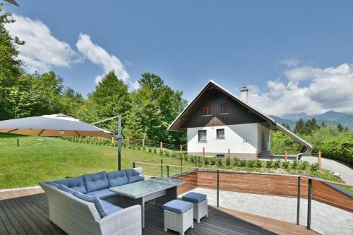 a deck with a table and chairs and a house at Villa Belica in Bohinj