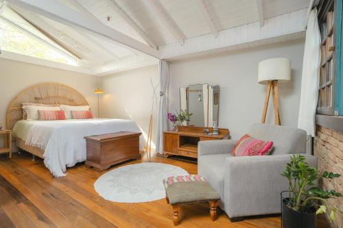 a bedroom with a bed and a chair at Studio Thai na praia in Barra de Ibiraquera