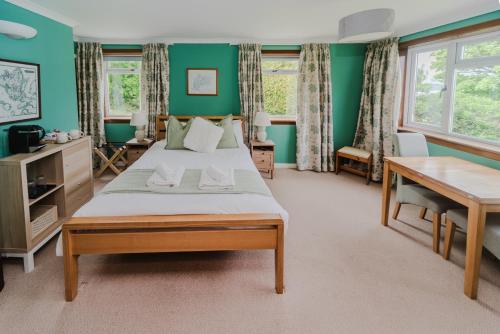 a bedroom with a large bed with green walls at The Otter Lodge in Broadford