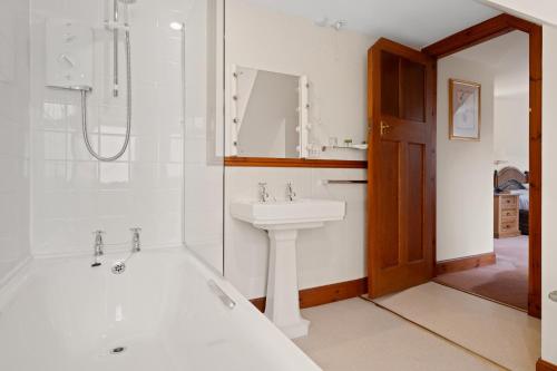 a bathroom with a bath tub and a sink at Keepers Cottage in Dunkeld