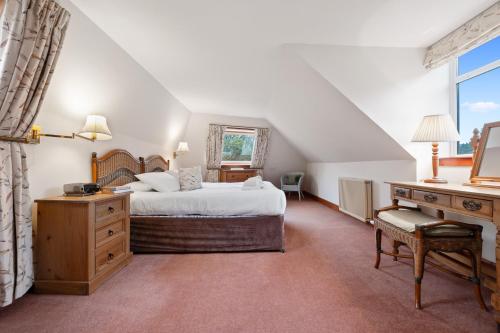 a bedroom with a large bed and a desk and a desk at Keepers Cottage in Dunkeld