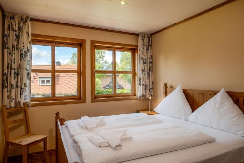 a bedroom with a large white bed with two windows at Heideröschen Park Heideröschen 7 in Zingst