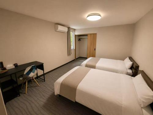 a hotel room with two beds and a desk at White Chalet Niseko in Niseko