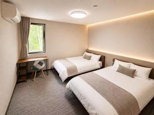 a hotel room with two beds and a desk at White Chalet Niseko in Niseko