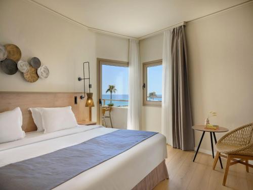ein Schlafzimmer mit einem Bett und Meerblick in der Unterkunft Atlantica Ocean Beach Resort in Maleme