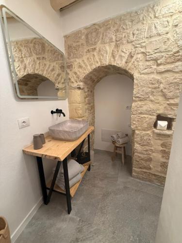 a bathroom with a sink and a stone wall at Gocce su Pietra in Sannicandro di Bari