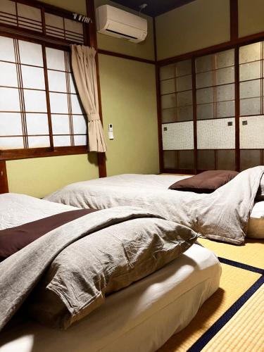 two beds sitting in a room with windows at ジャンハウス in Takayama