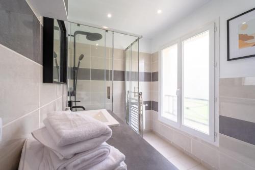 a bathroom with a sink and a shower with towels at La Maison du Bonheur - Appartements & Chambres à Gisors in Gisors