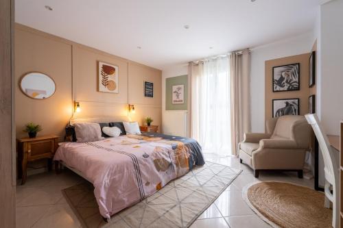 a bedroom with a large bed and a chair at La Maison du Bonheur - Appartements & Chambres à Gisors in Gisors