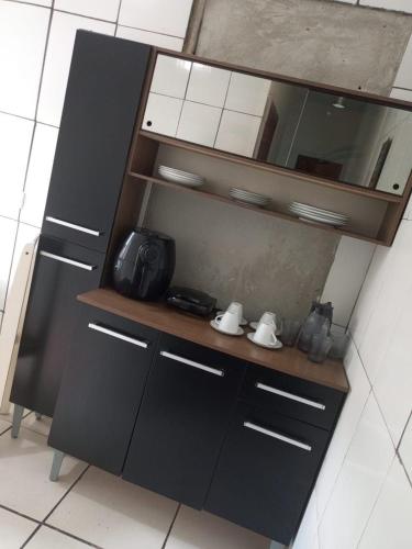 a kitchen with black cabinets and a mirror at Refúgio Charmoso 1 in Volta Redonda