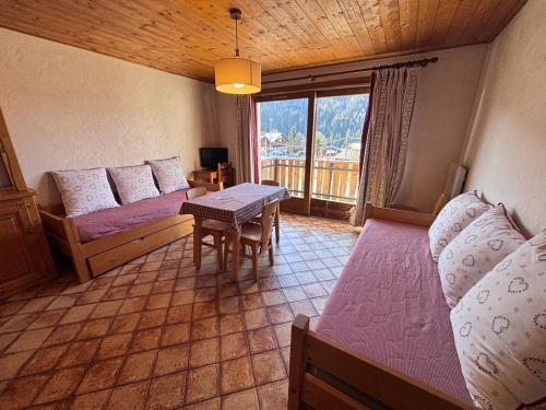 a bedroom with two beds and a table and a window at Studio Ban rouge, Chez Francine in Notre-Dame-de-Bellecombe