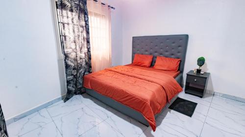 a bedroom with a bed with orange sheets and a window at Moonlight heaven suites in Limbe