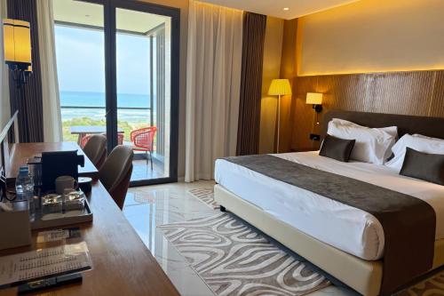 a hotel room with a large bed and a desk at Hotel Deauville El jadida in El Jadida