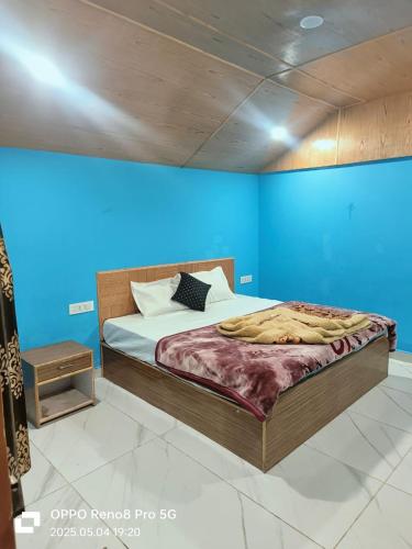 a bedroom with a bed with a blue wall at Mahi camping in Jagatsukh