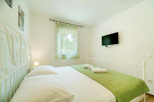 a white bedroom with a bed with towels on it at Holiday house Gloria in Vrbnik
