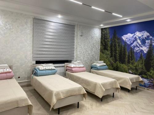a room with four beds and a painting on the wall at Tunduk Lux House in Teploklyuchinskoye