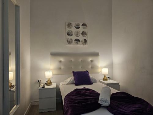 a bedroom with a bed with purple sheets and two lamps at Habitaciones Chueca in Madrid