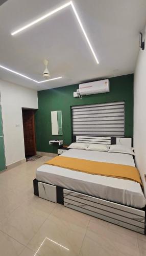 a bedroom with a large bed with a green wall at S J RESiDENCY in Trivandrum