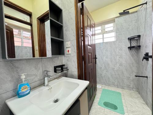a bathroom with a sink and a shower with a mirror at Riverview greenstar homes in Kisii