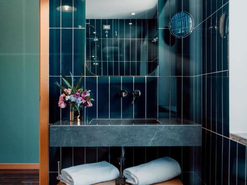 a bathroom with a sink and a vase of flowers at Hotel Mercure Roma Corso Trieste in Rome