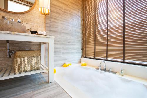 a bathroom with a white tub and a window at The Series Resort Khaoyai in Phayayen