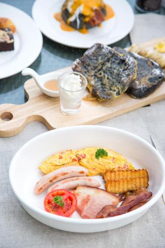 a plate of food with eggs sausage and corn on a table at The Series Resort Khaoyai in Phayayen