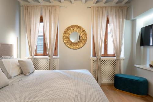 a bedroom with a bed with a mirror and two windows at La Piccola Atene Atelier in Pietrasanta