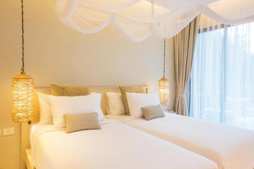 two white beds in a room with a window at The Series Resort Khaoyai in Phayayen