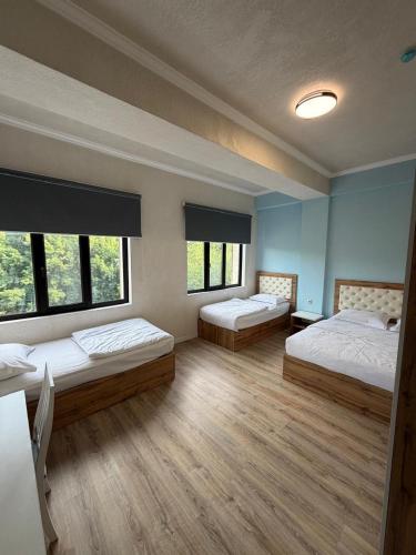 a room with three beds and two windows at Khan Plaza Hotel in Almaty